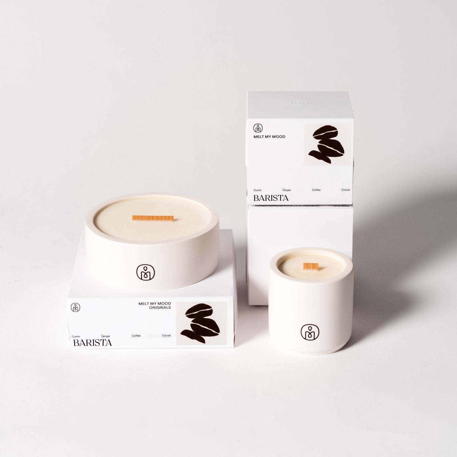 Fehér tégelyben és fehér dobozban elhelyezett Barista szójaviasz-gyertya – kávébab mintával és „MELT MY MOOD” felirattal –, világosszürke háttéren elrendezve.