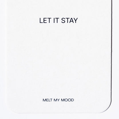 Közelkép egy lekerekített sarkú, fehér, téglalap alakú gardróbillatosítóról, amelynek felső részén a „LET IT STAY”, alsó részén pedig a „MELT MY MOOD” felirat látható fekete betűkkel.